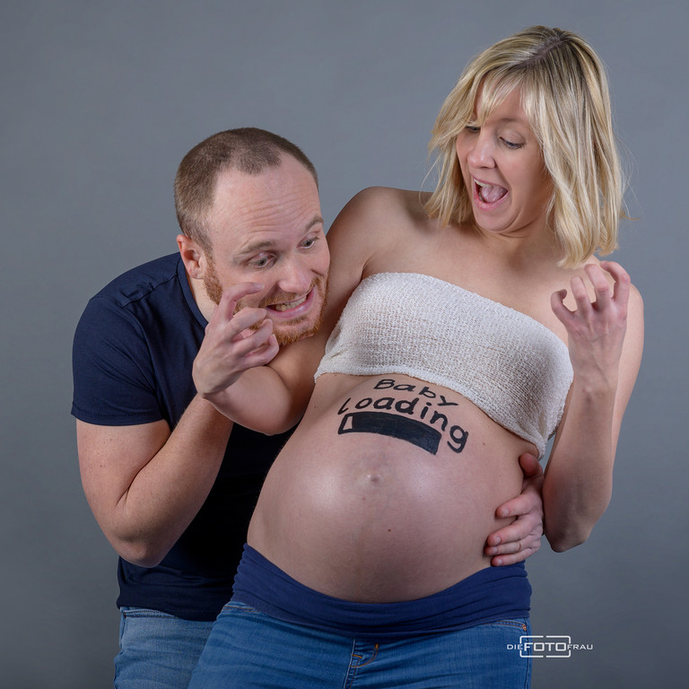 Babybauchshooting mit Partner, auf dem Bauch der Mutter wurde ein Loading-Symbol gezeichnet