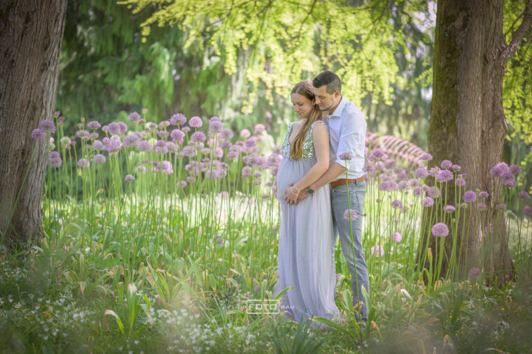 Babybauchshooting inmitten hoher Lauchblüten, die werdende Mutter trägt ein violettes Kleid
