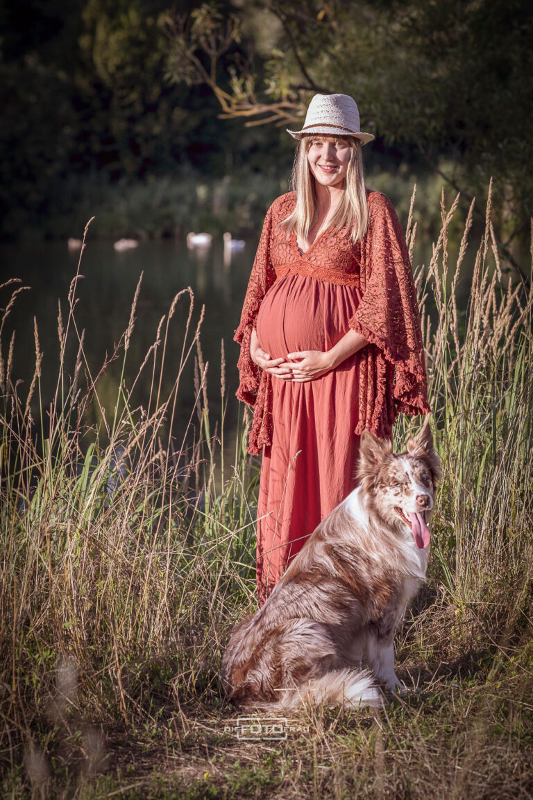 Babybauchshooting im Vintagestyle im hohen Gras am See mit Hund