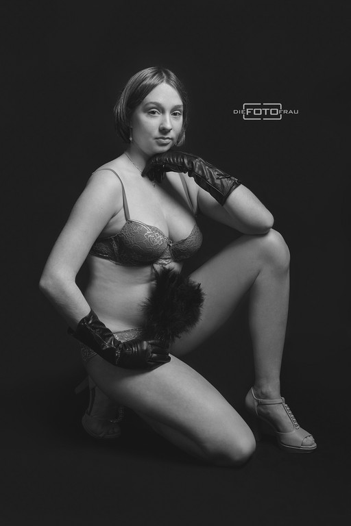 Boudoirfoto einer am Boden knieenden Dame mit Handschuhen und Federquaste in schwarzweiss, Fotostudio Linz