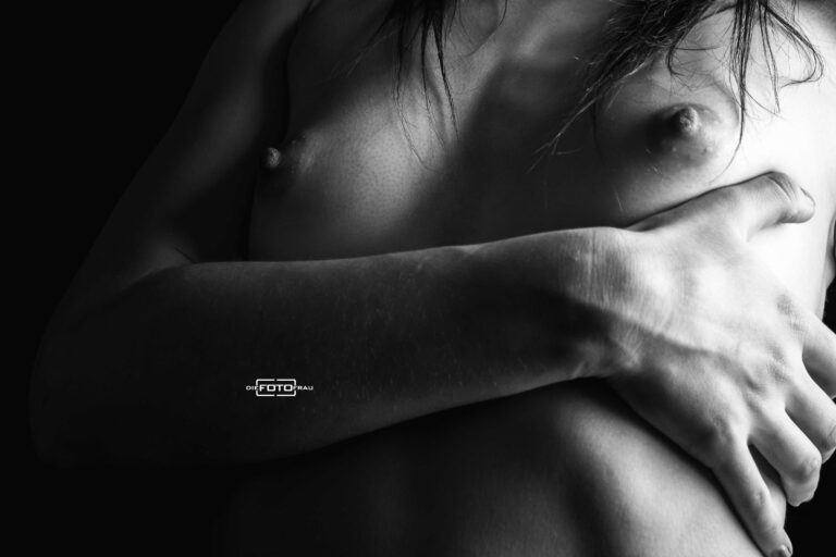 Boudoirfoto mit einem Ausschnitt der nackten Brust in schwarzweiss