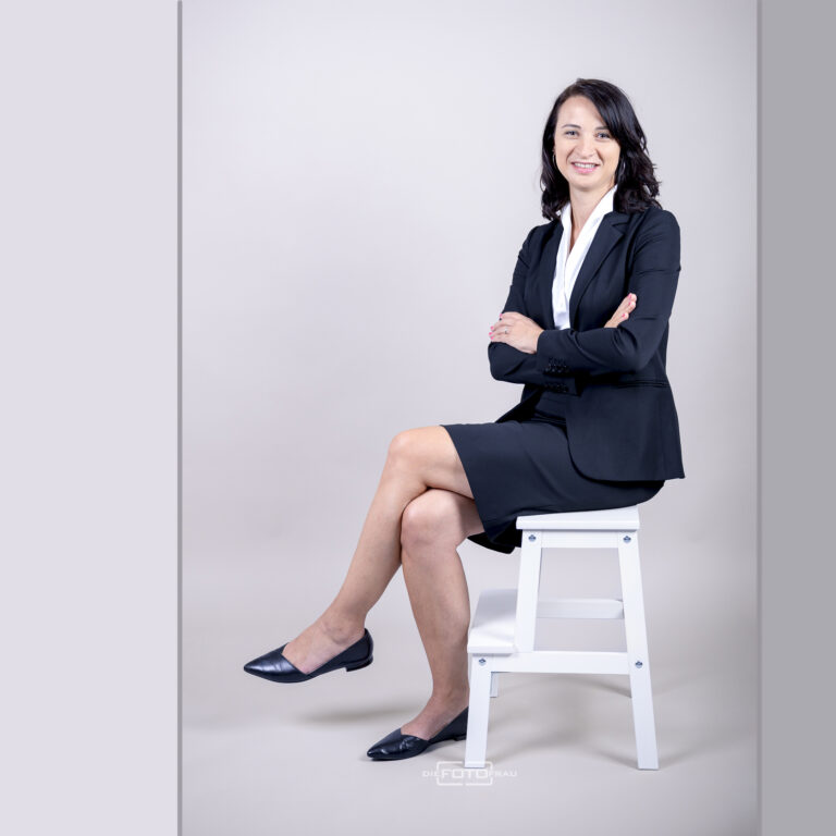 Businessportrait einer Dame im Kostuem auf einem Sessel sitzend im Fotostudio Linz