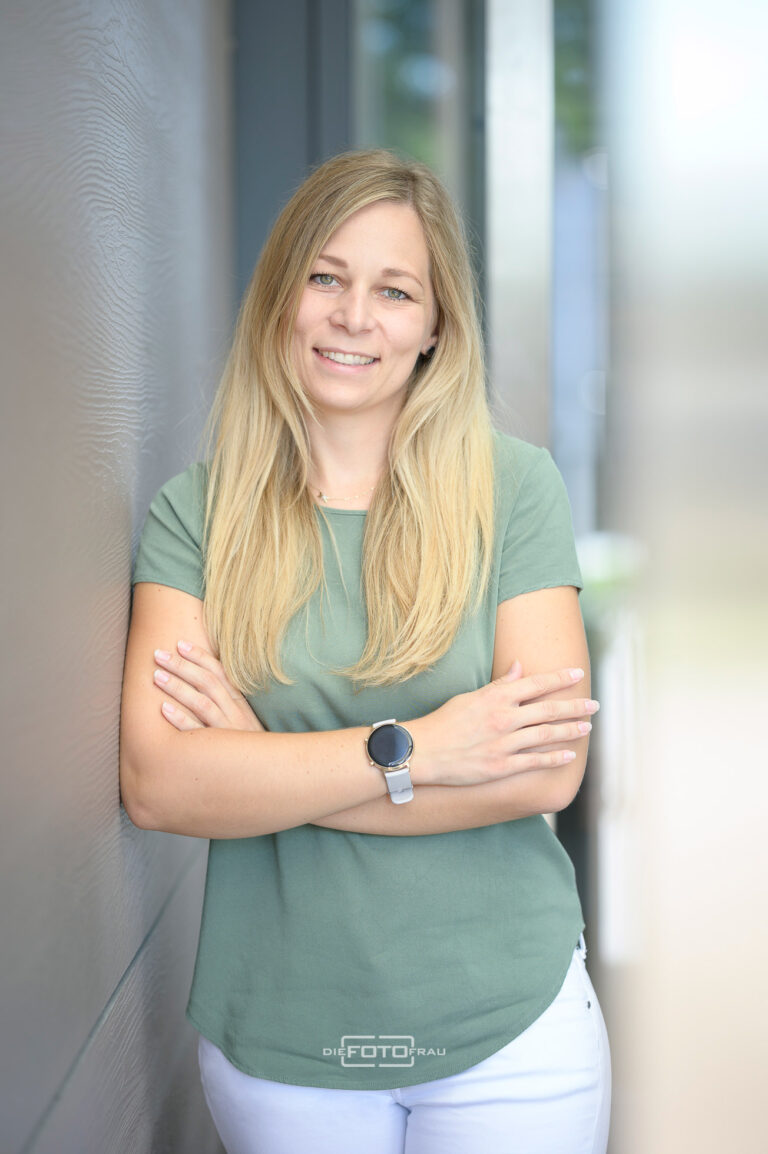 Businessportrait einer Frau in der Praxis ihrer Ordination, sie trägt ein grünes Shirt