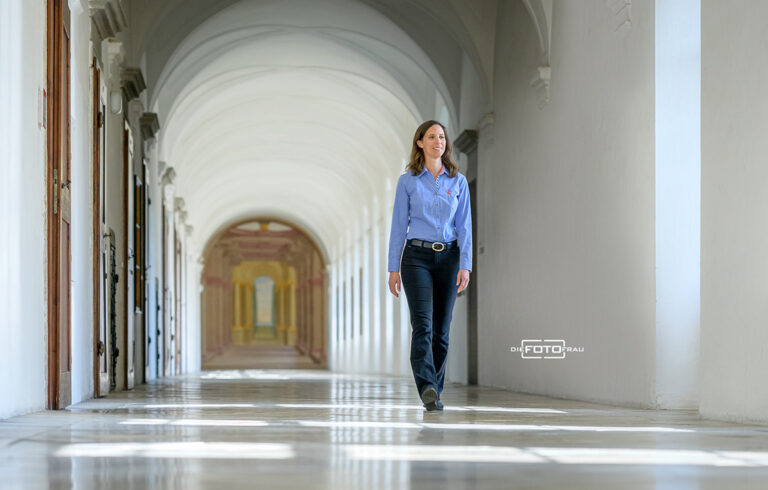 Businessportrait einer Dame in blauer Bluse in einem Marmorgang einer Kirche