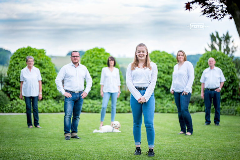 Familienfoto im Garten, die Personen sind versetzt angeordnet und der Fokus liegt auf dem Kind vorne