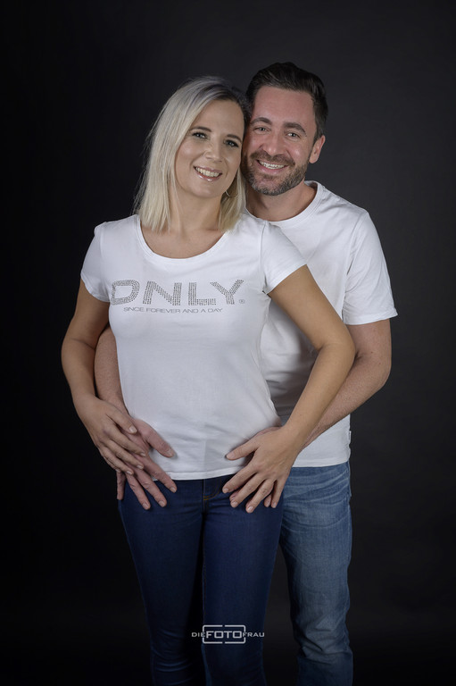 Paarfoto eines jüngeren Paares im Fotostudio Linz vor dunkler Kulisse