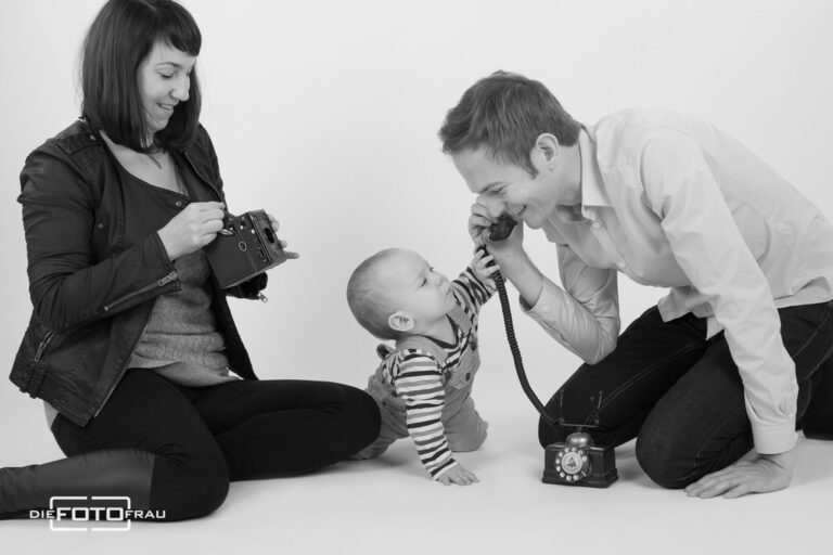 Familienfoto in schwarzweiss, das Kind spielt mit einem antiken Telefon