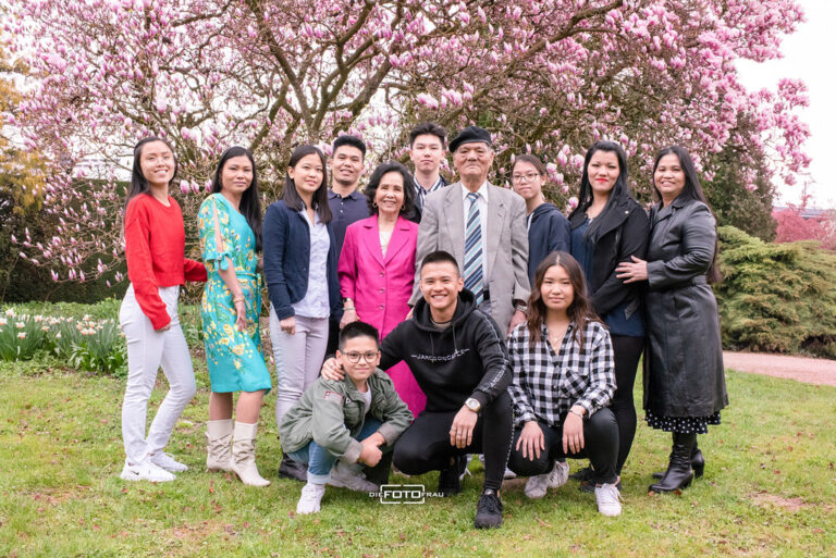 Familienfoto und Gruppenbild einer vietnamesischen Familie vor einem blühenden Magnolienbaum