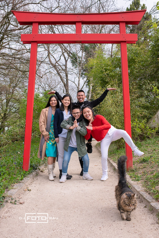 Familienfoto einer vietnamesischen Familie vor einem roten Zentor mit Katze