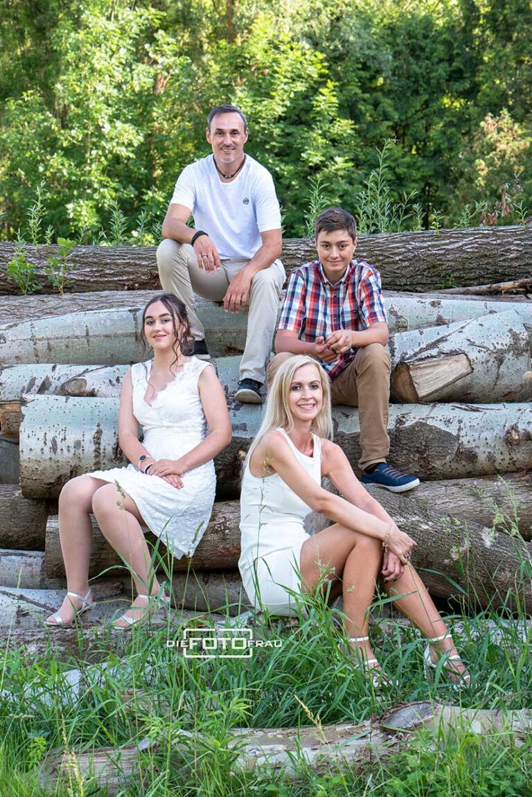 Familienfoto auf Baumstämmen sitzend