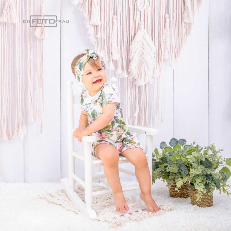 Erster Geburtstag eines Mädchens im Fotostudio Linz, es trägt Bohokleidung, dahinter sieht man einen Makramee-Wandbehang