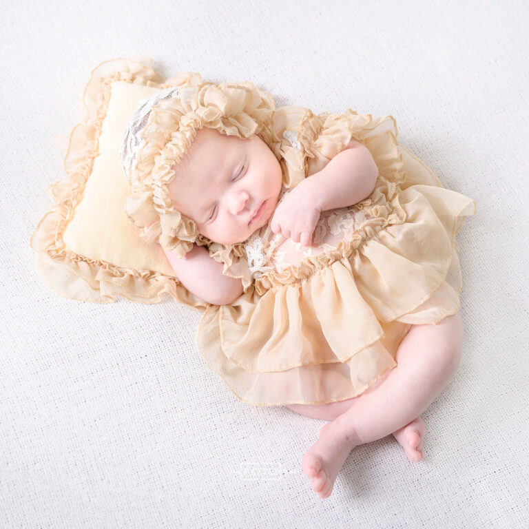 Neugeborenenfoto mit schlafendem Baby in Prinzessinnenkleid auf Kopfpolster