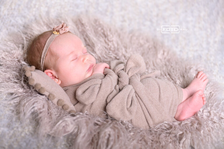 Neugeborenenfoto mit schlafendem Baby auf beigen Decken und Tüchern