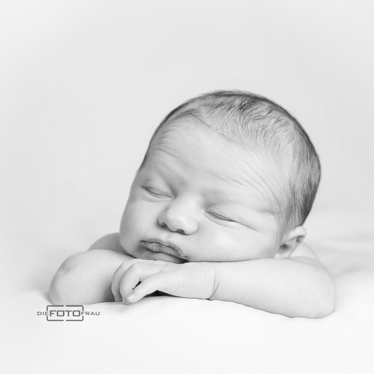 Neugeborenenfoto mit schlafendem Baby, der Kopf liegt auf den Vorderarmen