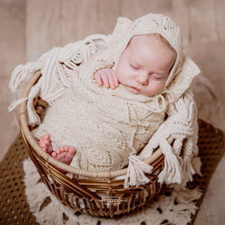 Neugeborenenfoto mit Baby in handgestrickten Decken in einem Korb gebettet, Bohostyle