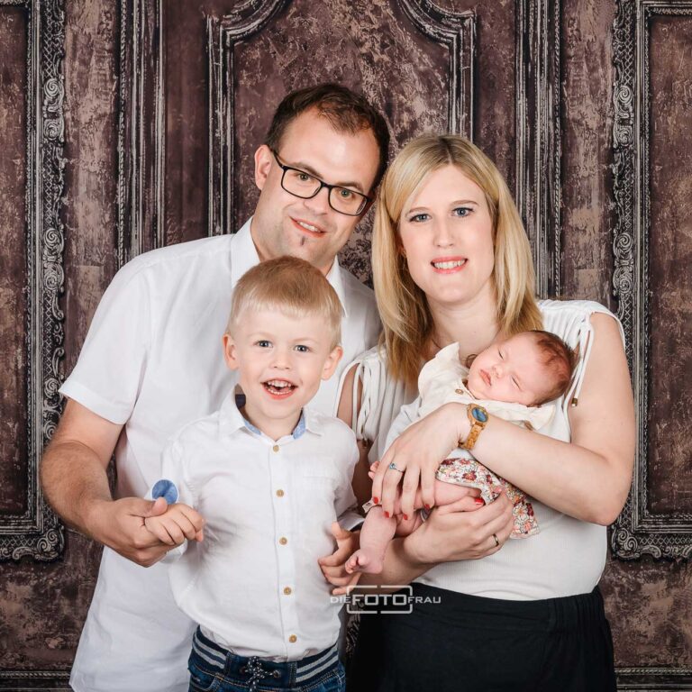 Neugeborenenfoto mit schlafendem Baby mit Eltern und Bruder