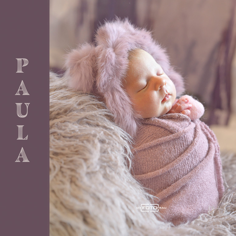 Neugeborenenfoto mit schlafendem Baby, angelehnt an einen rosa Fellpolster