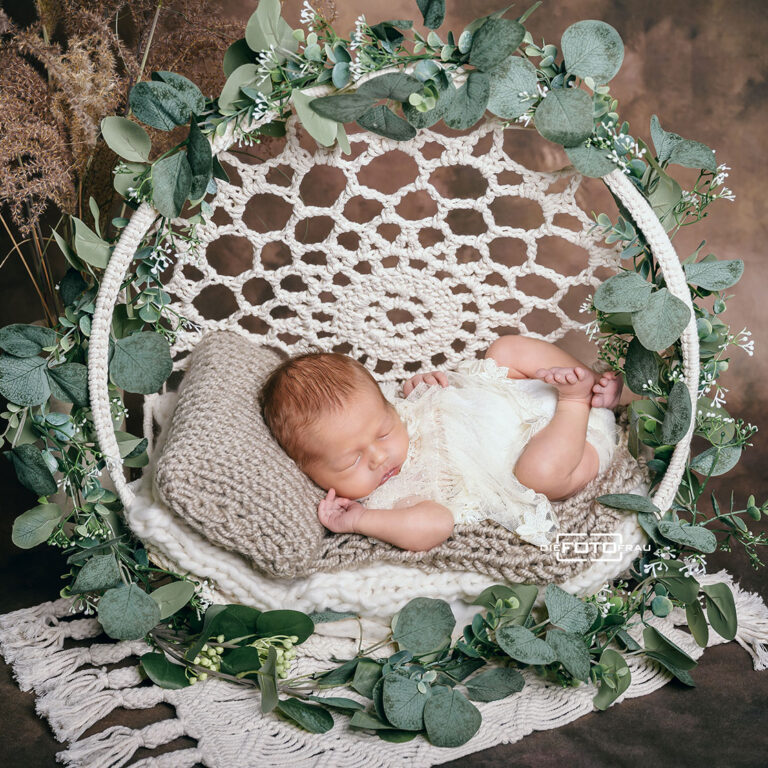 Neugeborenenfoto mit schlafendem Baby, dieses liegt in einem Traumfänger aus Makramee