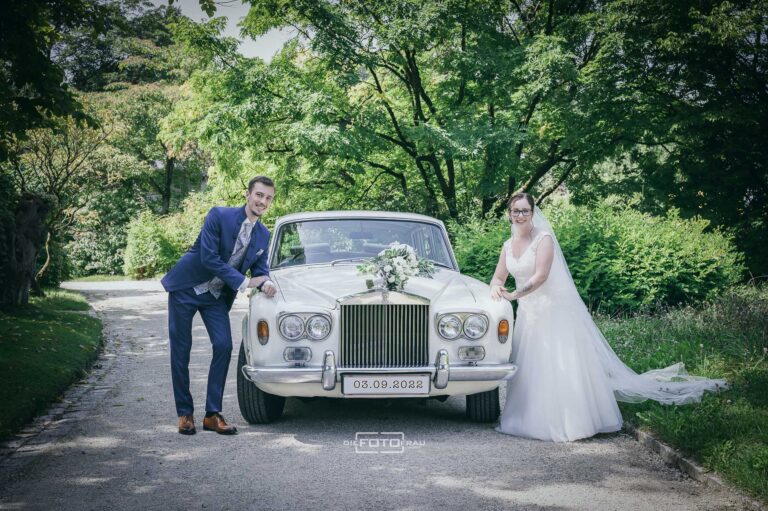 Brautpaar fährt mit dem Brautauto zur Hochzeit im Botanischen Garten
