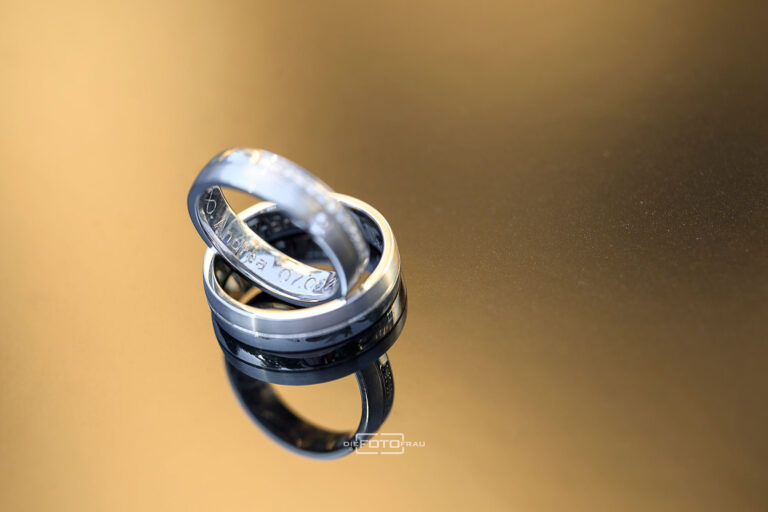 Eheringe liegen auf einem Metall, das durch die Abendsonne golden schimmert.