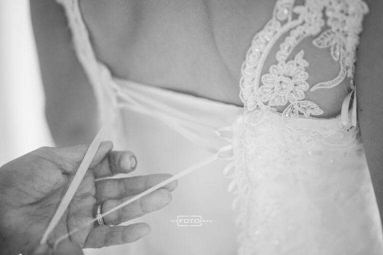 Brautmutter hilft der Tochter beim Anziehen des Brautkleides beim Gettingready, schwarzweisses Foto