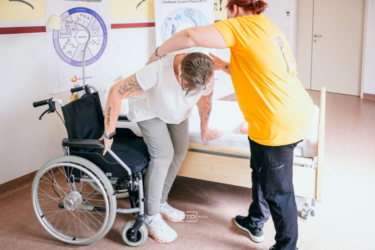 Kinästhetikerin und Patientin vom Rollstuhl aufstehend