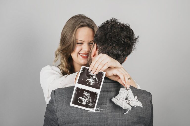 Pärchen hält Ultraschall bild ihres ungeborenen Babies in die Kamera, aufgenommen im Fotostudio DieFotoFrau